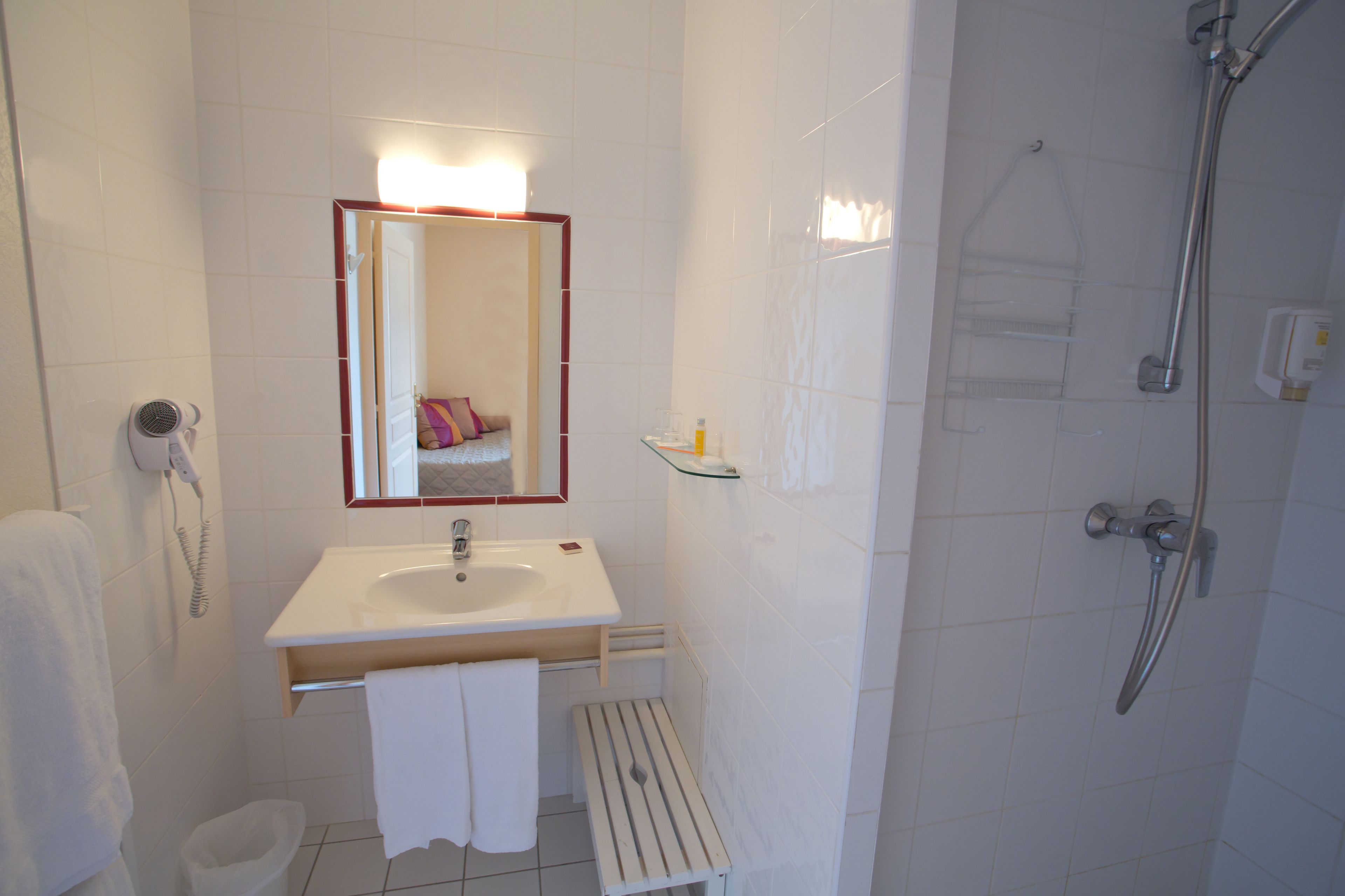 A bathroom with a sink, mirror, towel rack, and shower.