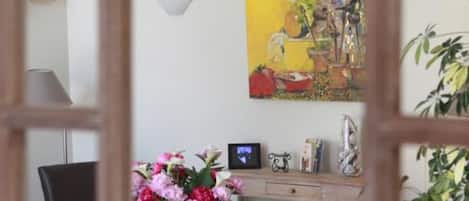Uma sala de jantar com uma mesa de madeira, cadeiras e um quadro na parede.