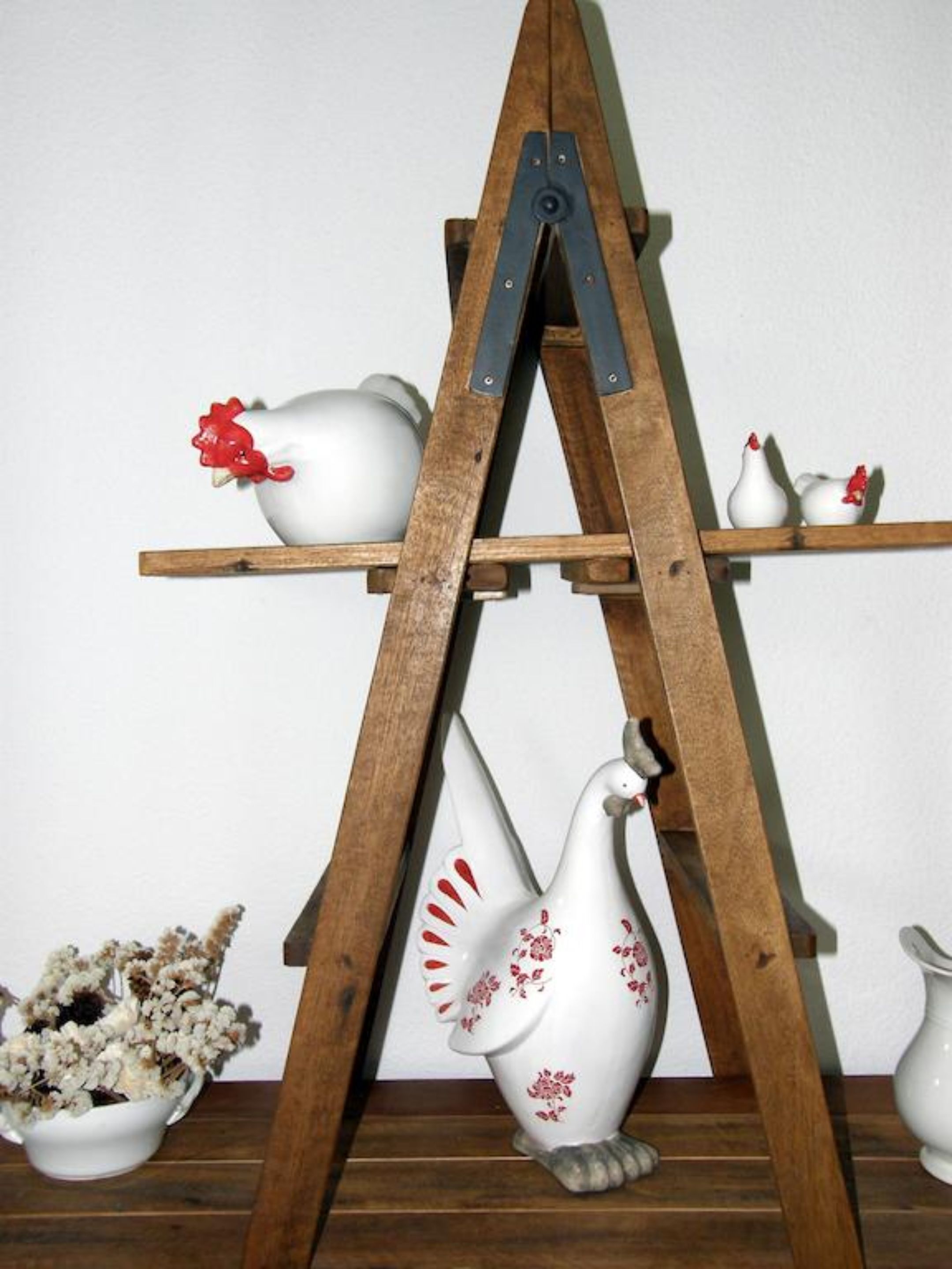 A wooden easel with ceramic bird sculptures and a bowl of dried flowers.