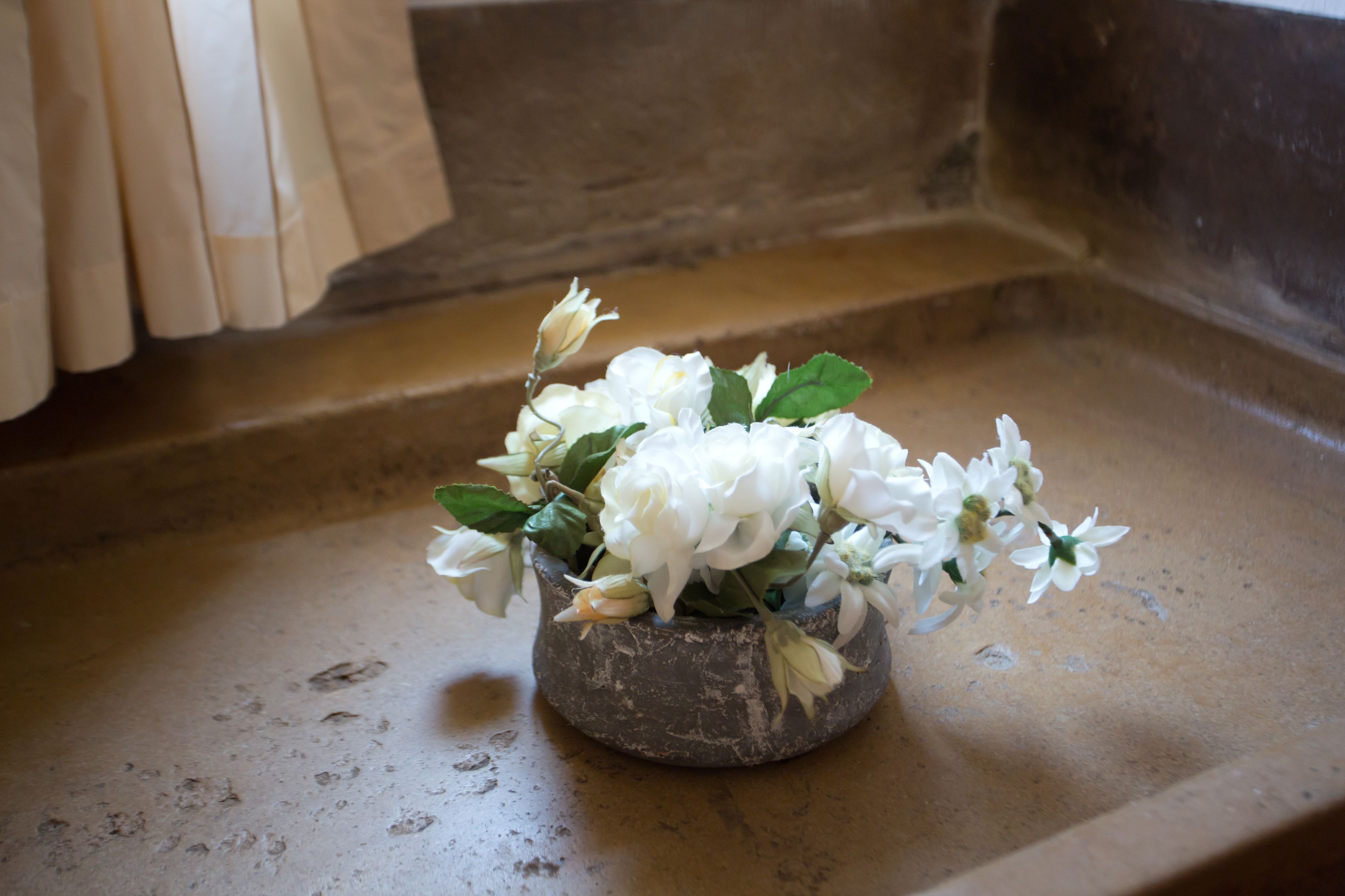 A stone bowl with white flowers on a stone ledge.