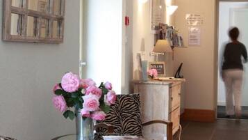 A room with a round wooden table, zebra-patterned chairs, a vase of pink flowers, and a mirror on the wall.