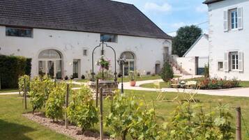 Traditional European-style building with a central entrance and a well-maintained garden with seating area.