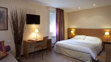 Une chambre d’hôtel équipée d’un lit, d’un bureau, d’une chaise, d’une télévision et de lampes.