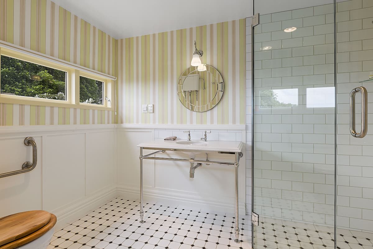 A bathroom with a white sink, mirror, and glass shower enclosure.