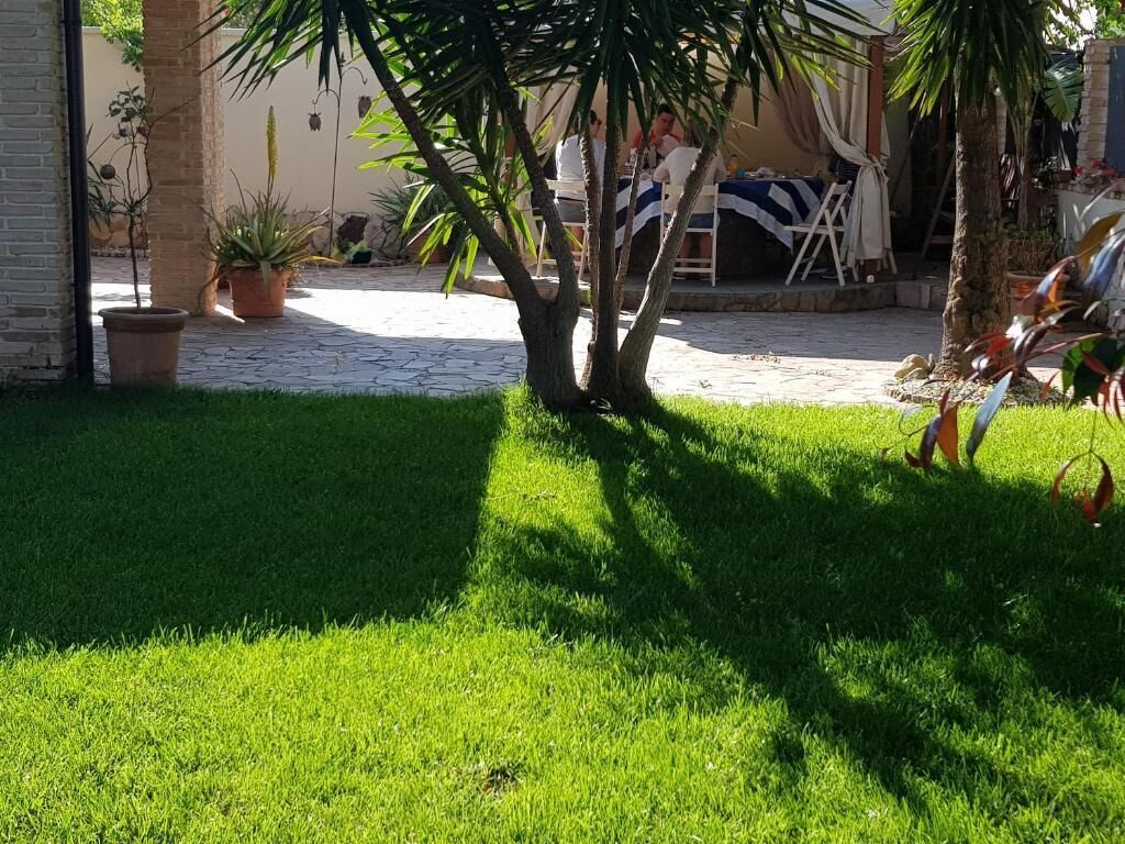 A courtyard with a well-maintained lawn, potted plants, and a seating area with tables and chairs.