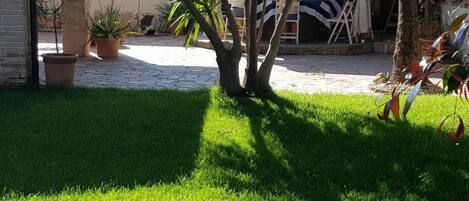 A courtyard with a well-maintained lawn, potted plants, and a seating area with tables and chairs.
