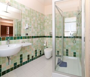 Un baño con cabina de ducha de vidrio, un lavamanos y un inodoro.