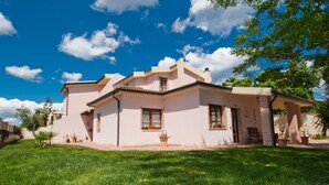 A pink house with a tiled roof, a small porch, and a well-maintained lawn. - Gentarrubia - B&B (Capoterra)
