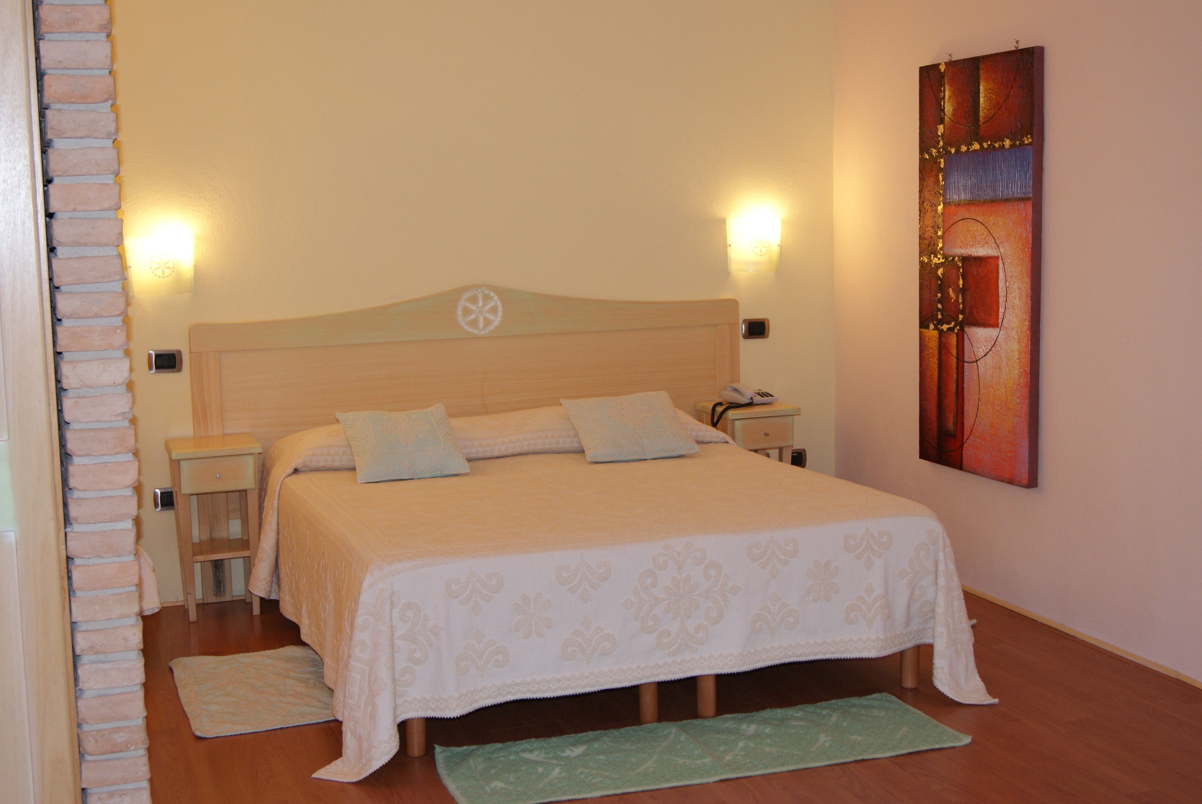 A neatly arranged bedroom with a bed, bedside tables, a nightstand, a wall-mounted artwork, and a green rug.