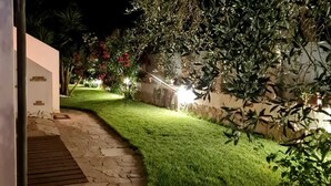 A well-lit garden pathway leading to a building with a stone wall and lush greenery. - Gentarrubia - B&B (Capoterra)