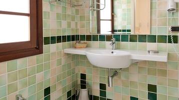 Een badkamer met een wit wastafel, een hygiëneschuimer en een betegelde muur.