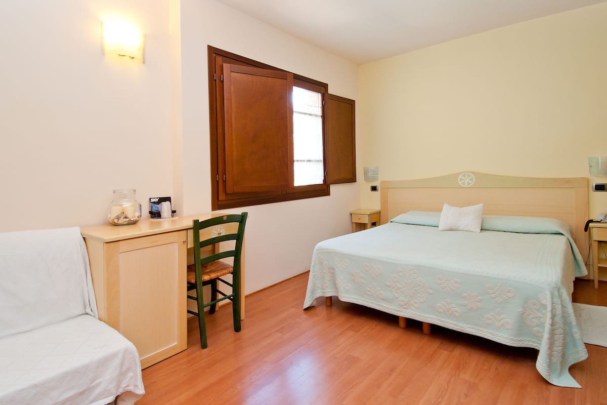 A bedroom with a bed, a desk, and a chair.