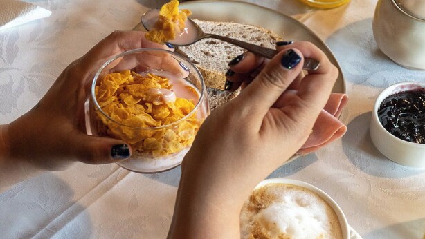 A breakfast setting with croissants, muffins, and a glass of orange juice on a table. - Wesley House Hosteria Boutique (San Martín de los Andes)