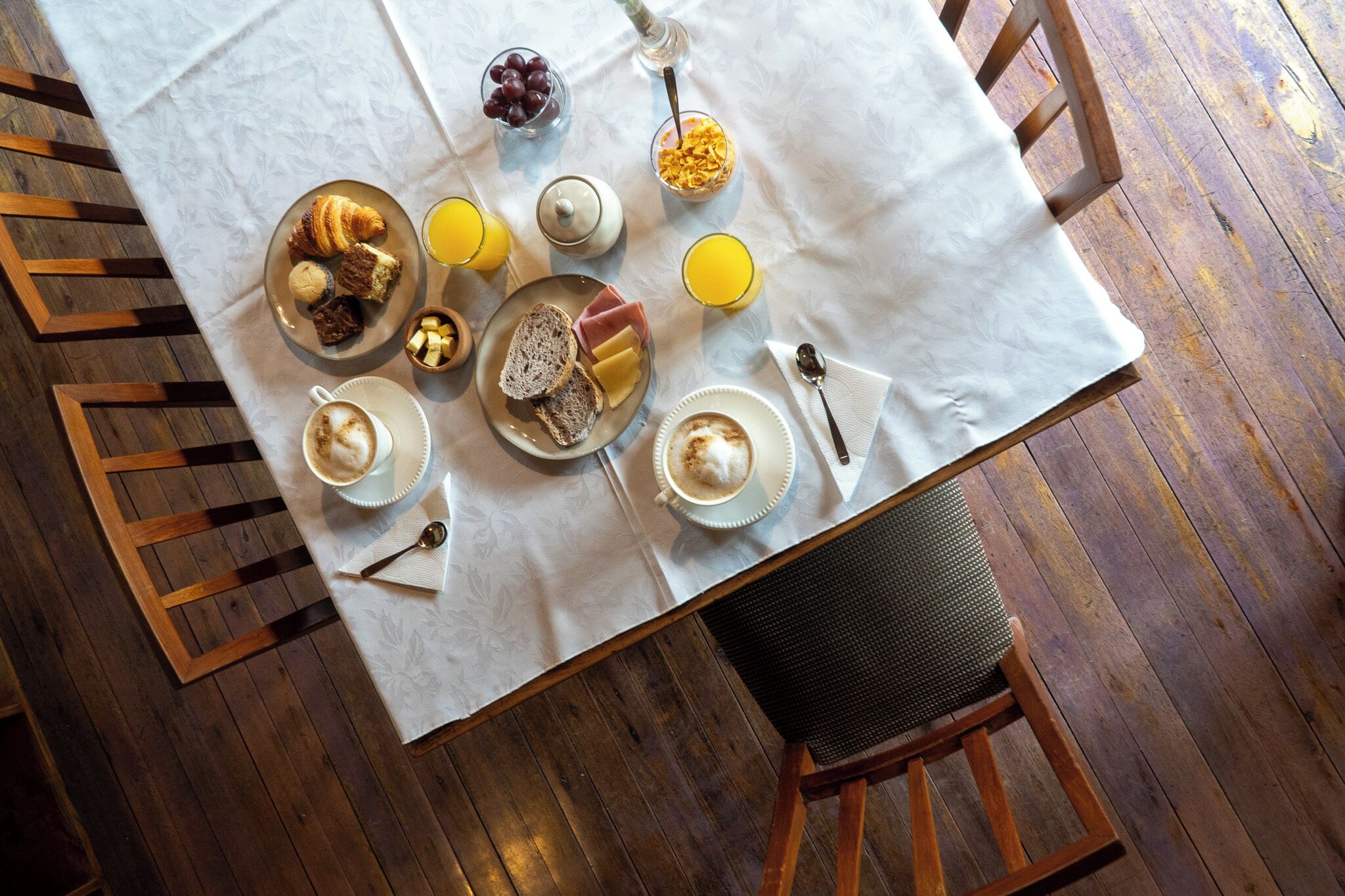 Ein Frühstückstisch mit Croissants, Früchten, Saft und Kaffee.