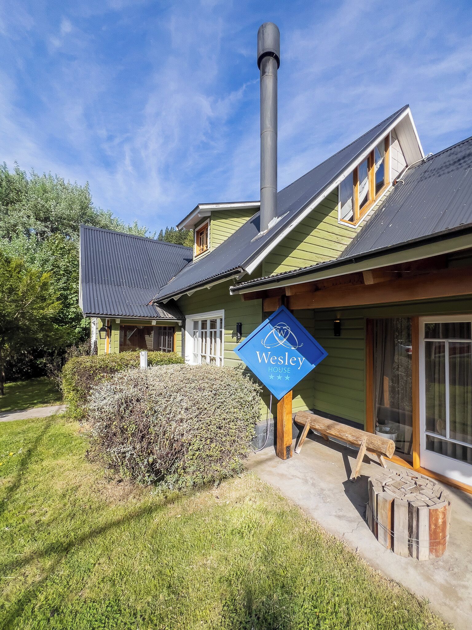 Un edificio verde con un letrero azul que dice "Wesley HOUSE" y una chimenea.