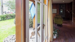A wooden interior with a door leading outside, a green wall, and a framed picture on the wall.