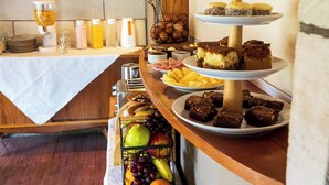 A buffet table with various food items, including fruits, pastries, and desserts.