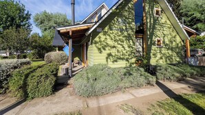 A green lodge with a chimney, a porch, and a sign indicating it's a hostel.