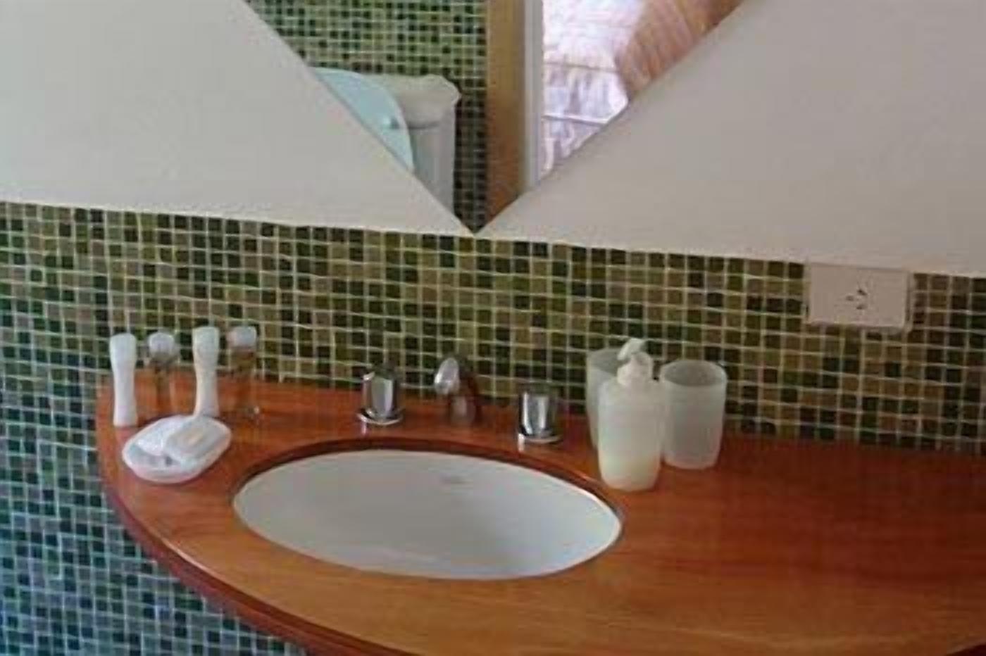 Un baño con tocador de madera, un lavabo blanco y un espejo.