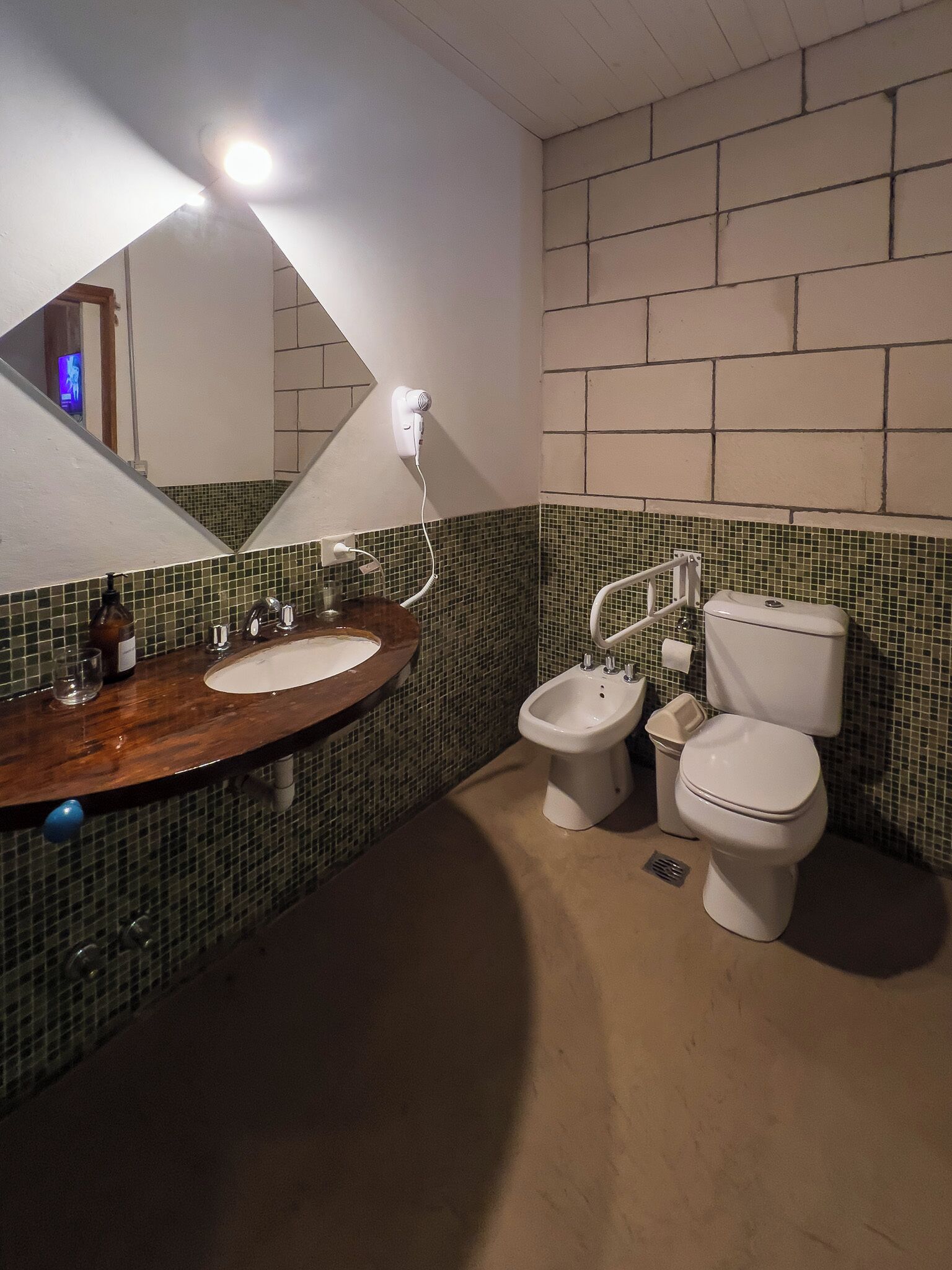 Ein Badezimmer mit einem Holzkosmetikschrank, einem Spiegel, einem Bidet und einer Toilette.