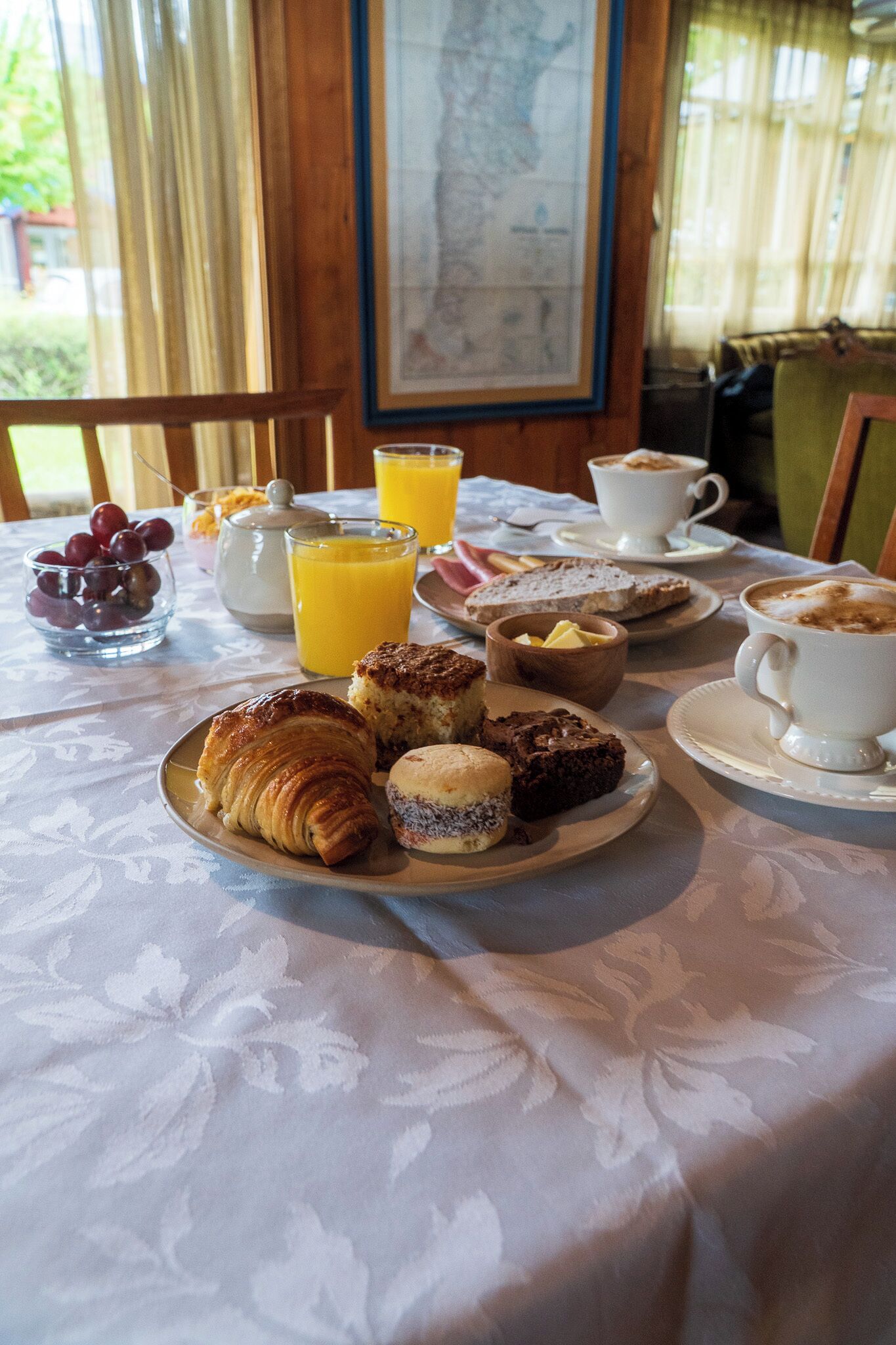 Una mesa de desayuno con cruasanes, muffins y un vaso de jugo de naranja.