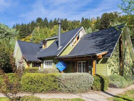 A green house with a black roof, a chimney, and a sign that says "Wesley House".