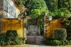 A gated entrance with a stone wall, a metal gate, and a staircase leading up. - Quinta da Bouça d'Arques (Viana do Castelo)