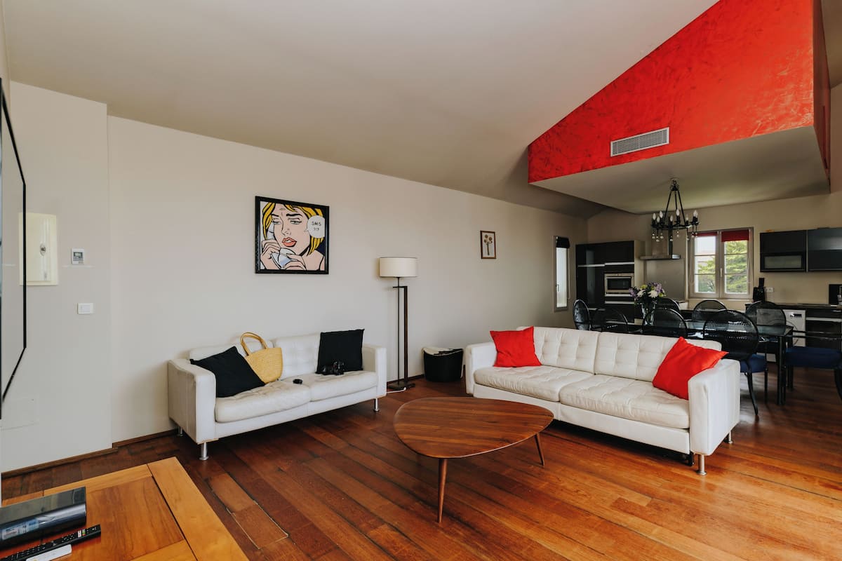Un salon moderne avec un canapé blanc, une table basse en bois et un mur d’accent rouge.