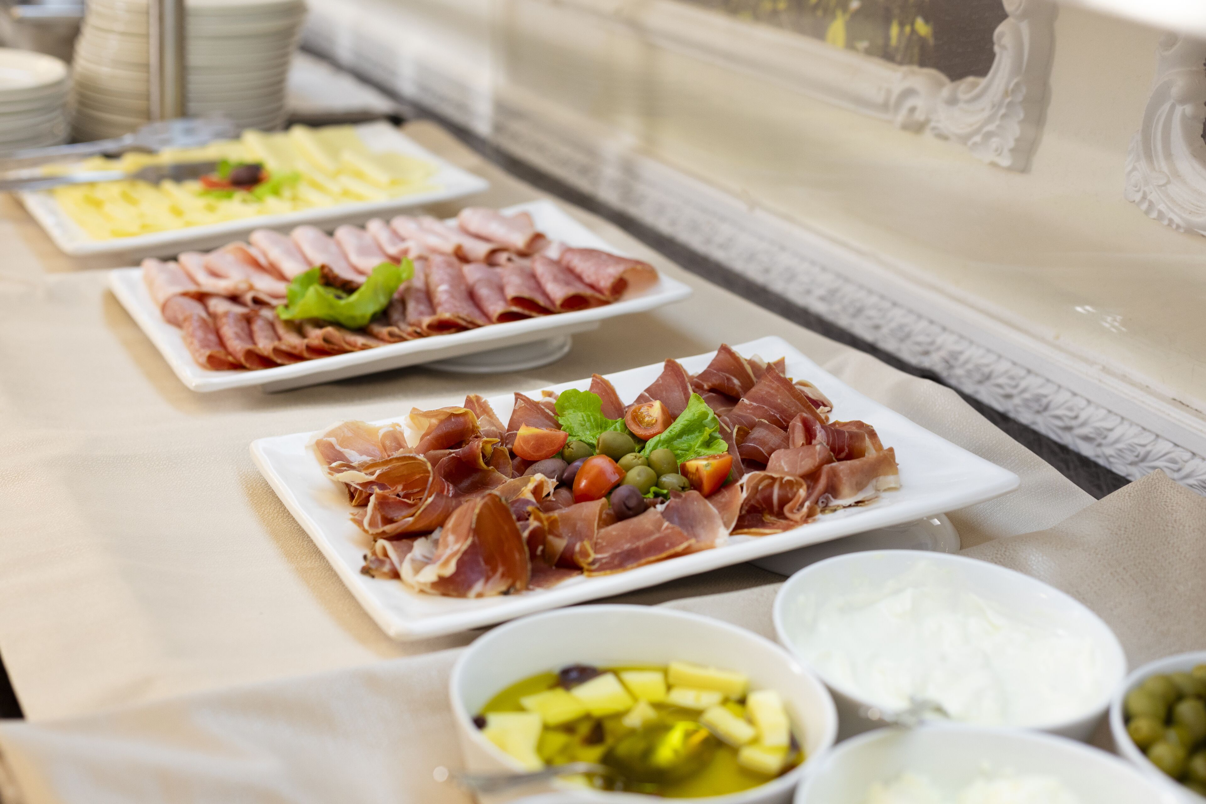 A buffet table with various food items including meats, cheeses, and olives.