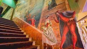 A staircase with a mural depicting historical figures and a cityscape.