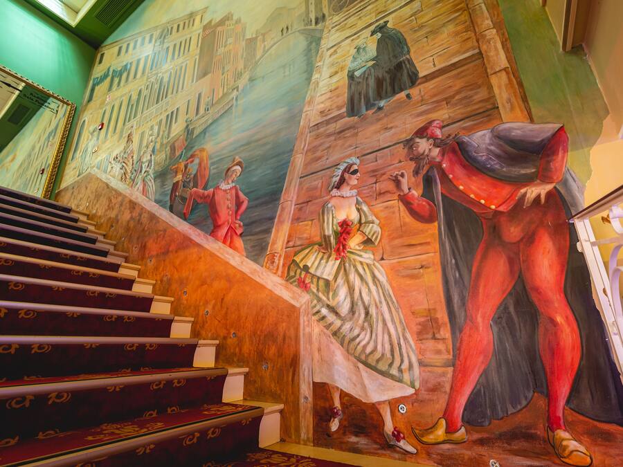 Una escalera con un mural que representa figuras históricas y un paisaje urbano.