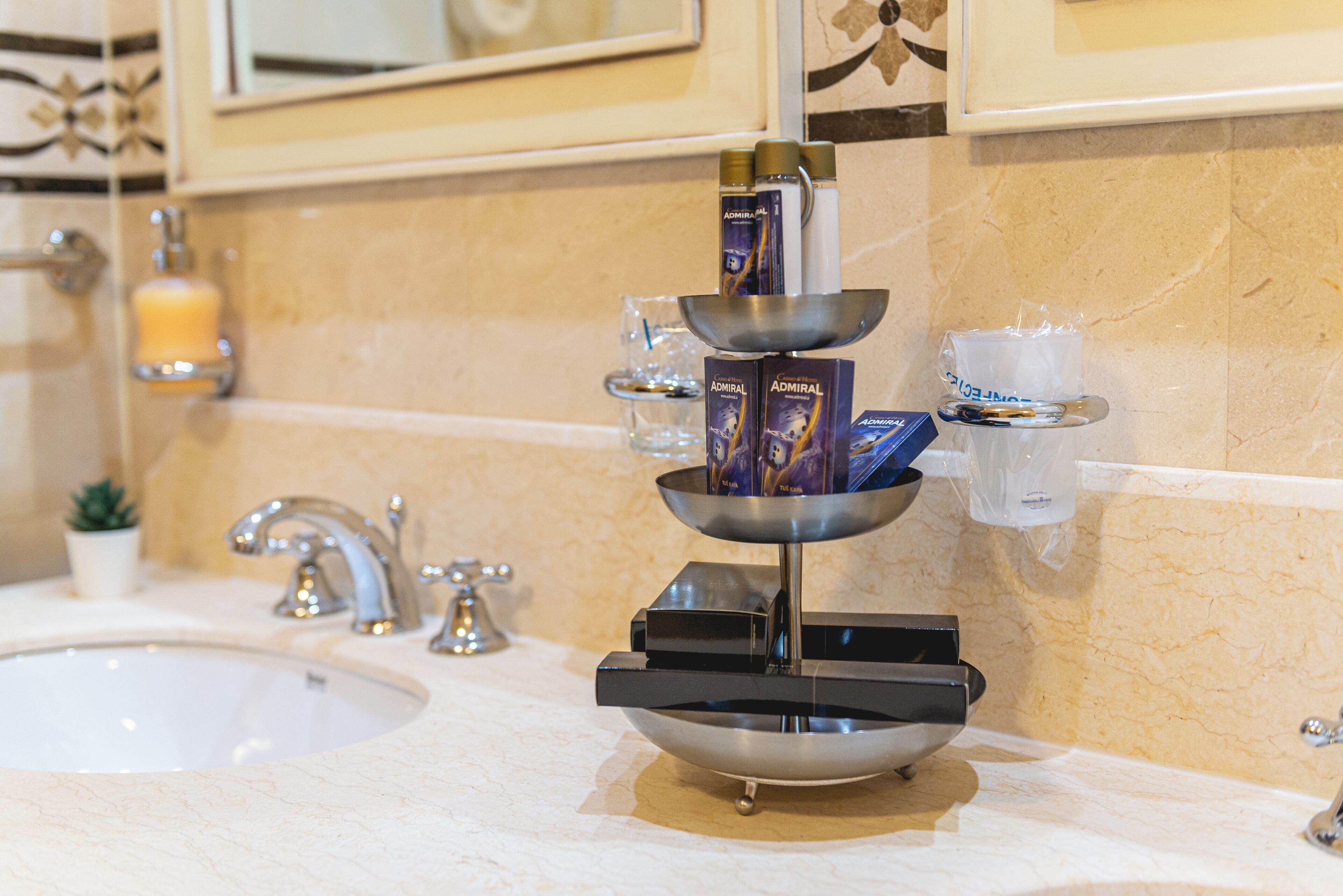 A bathroom with a sink, two faucets, a mirror, and a soap dispenser.