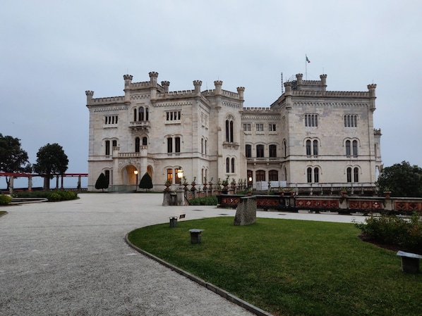 A large, historic building with a symmetrical facade, multiple windows, and a flag on top.