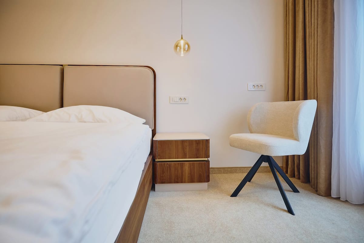 Un dormitorio moderno con una cama, mesitas de noche, una silla y una lámpara colgante.