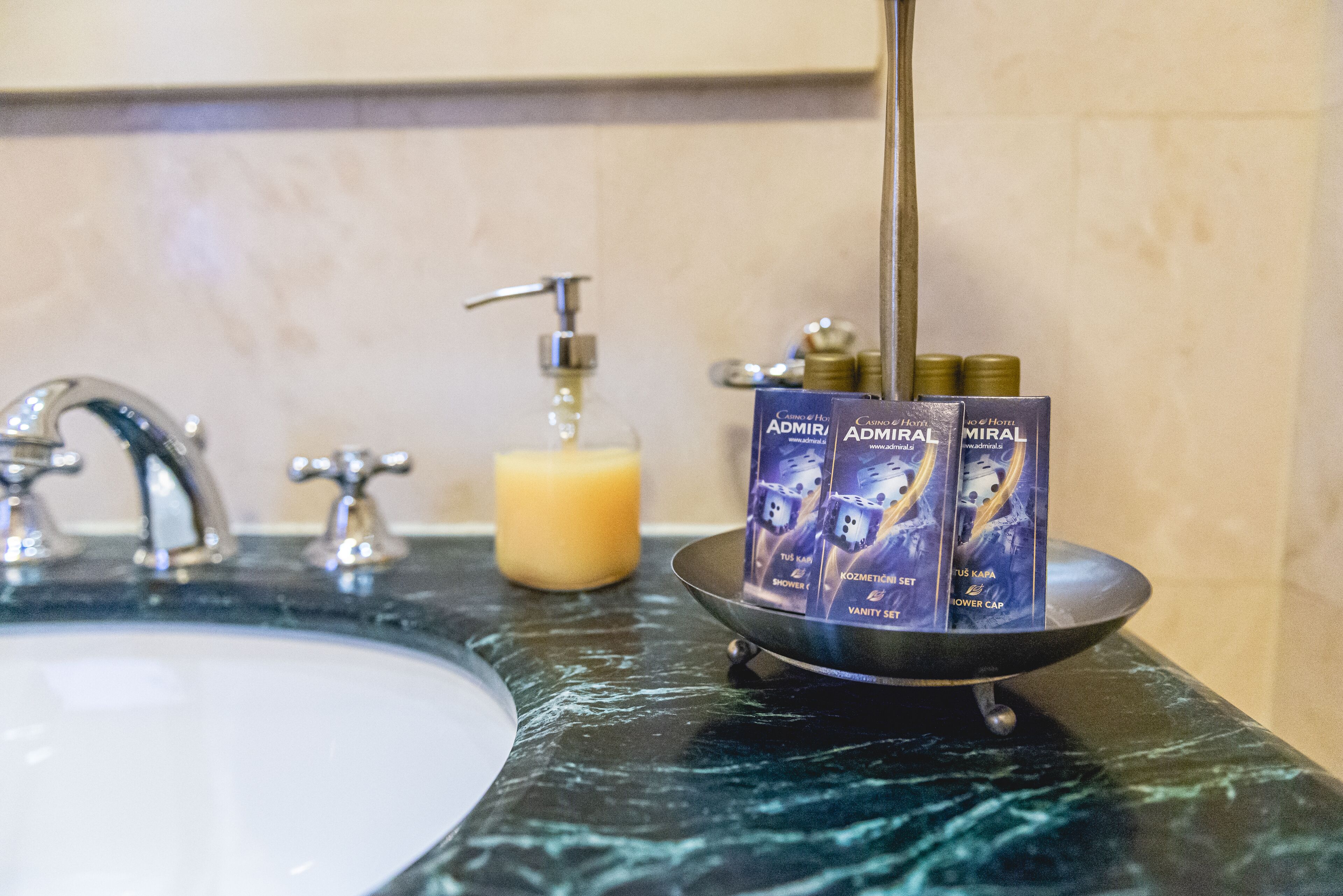 Un lavabo de salle de bain avec un plan de toilette en marbre, un distributeur de savon et un flacon de savon liquide.