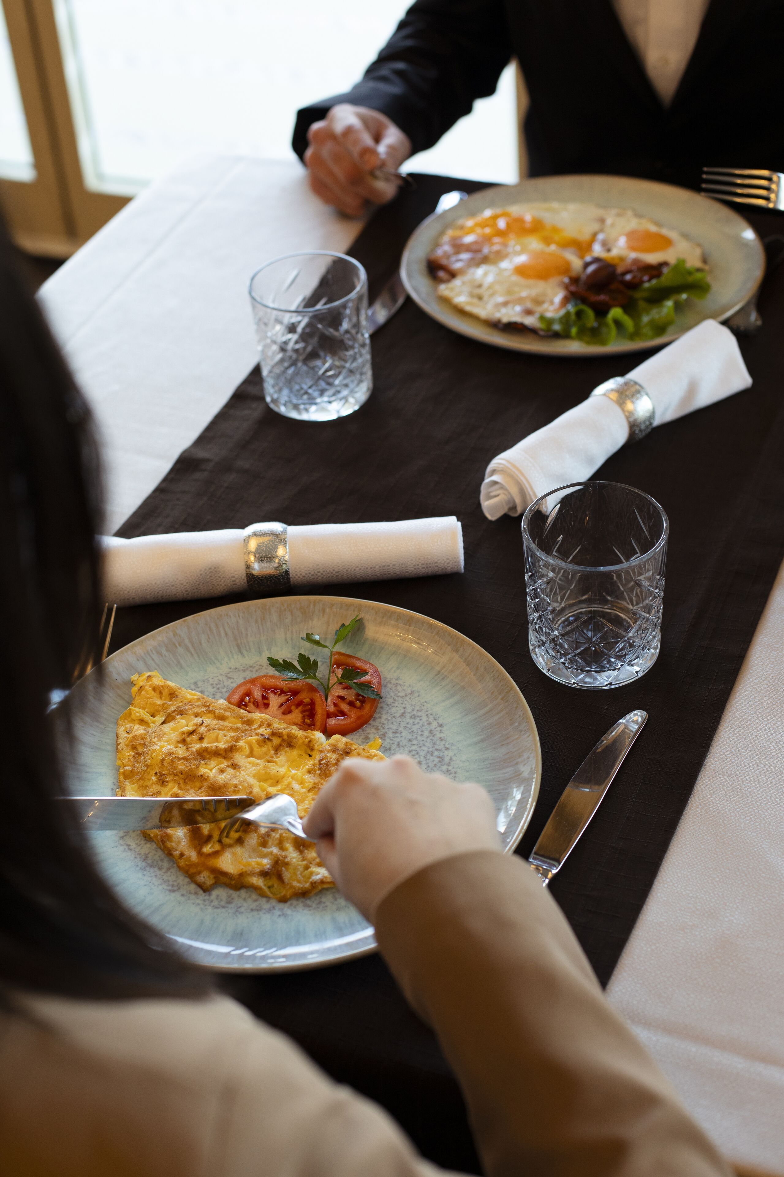 Uma mesa de jantar com pratos de comida, um copo de água e talheres.