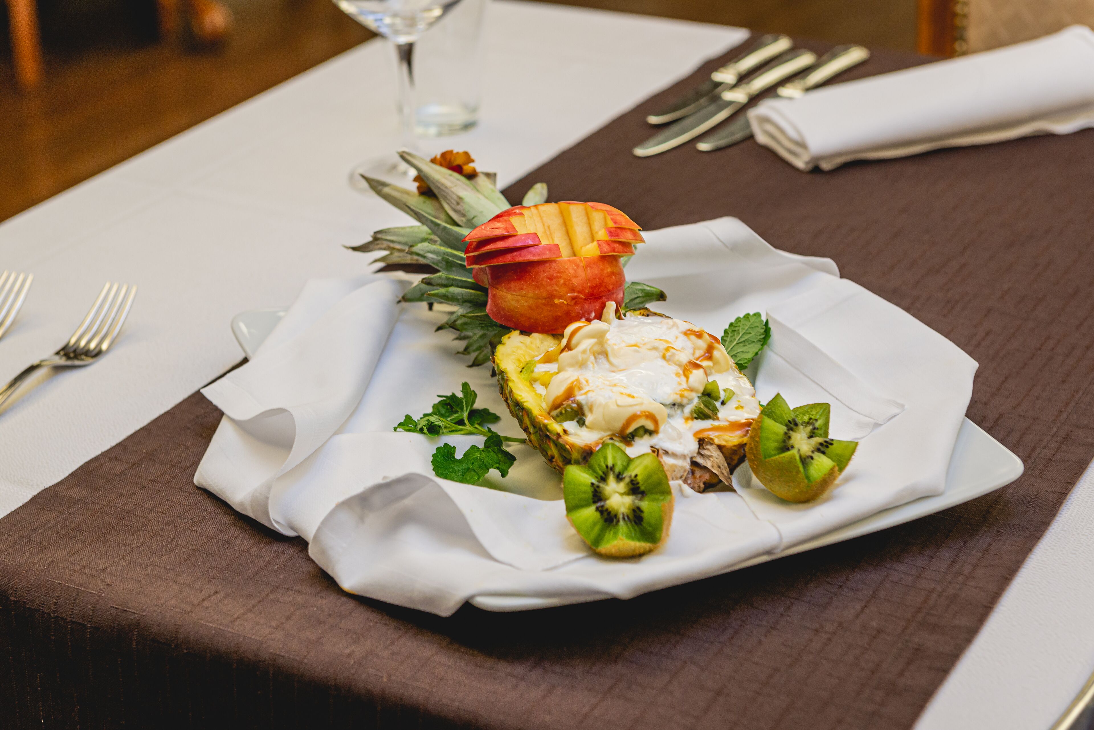 A plated dish with a fruit garnish, accompanied by a glass of water and cutlery on a table.
