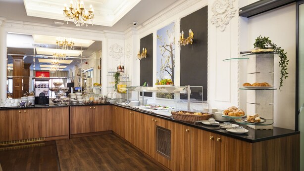 A modern kitchen with wooden cabinets, a black countertop, and a glass display case.