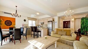 A modern living room with a sofa set, dining area, and kitchen.