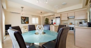 A modern dining area with a glass table, six chairs, and a decorative centerpiece.