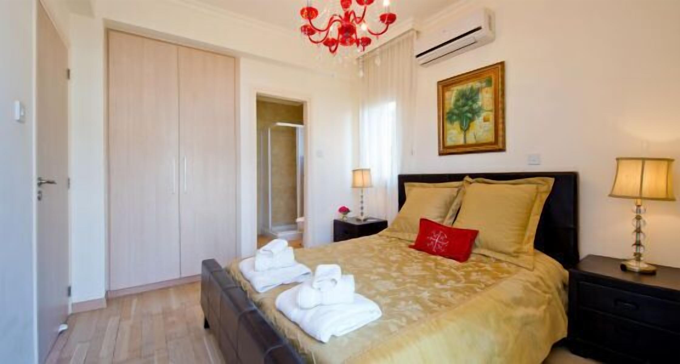 Una habitación de hotel con una cama, una mesita de noche, una lámpara, un cuadro y un equipo de aire acondicionado.