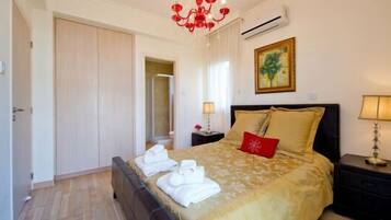Una habitación de hotel con una cama, una mesita de noche, una lámpara, un cuadro y un equipo de aire acondicionado.