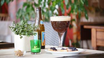 A table with a bottle, a glass of beer, a candle, and a plate of food.