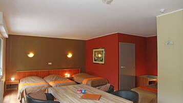 Habitación de hotel con dos camas individuales, una mesa de madera, una silla y un escritorio con una computadora portátil.