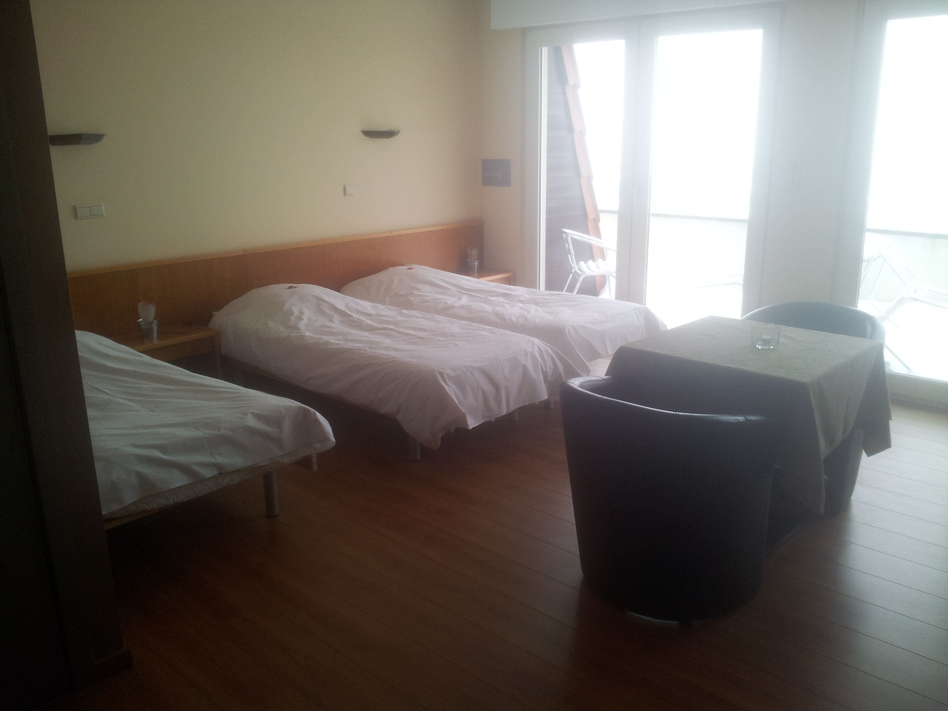 Quarto de hotel com duas camas de solteiro, uma mesa pequena e uma lixeira.