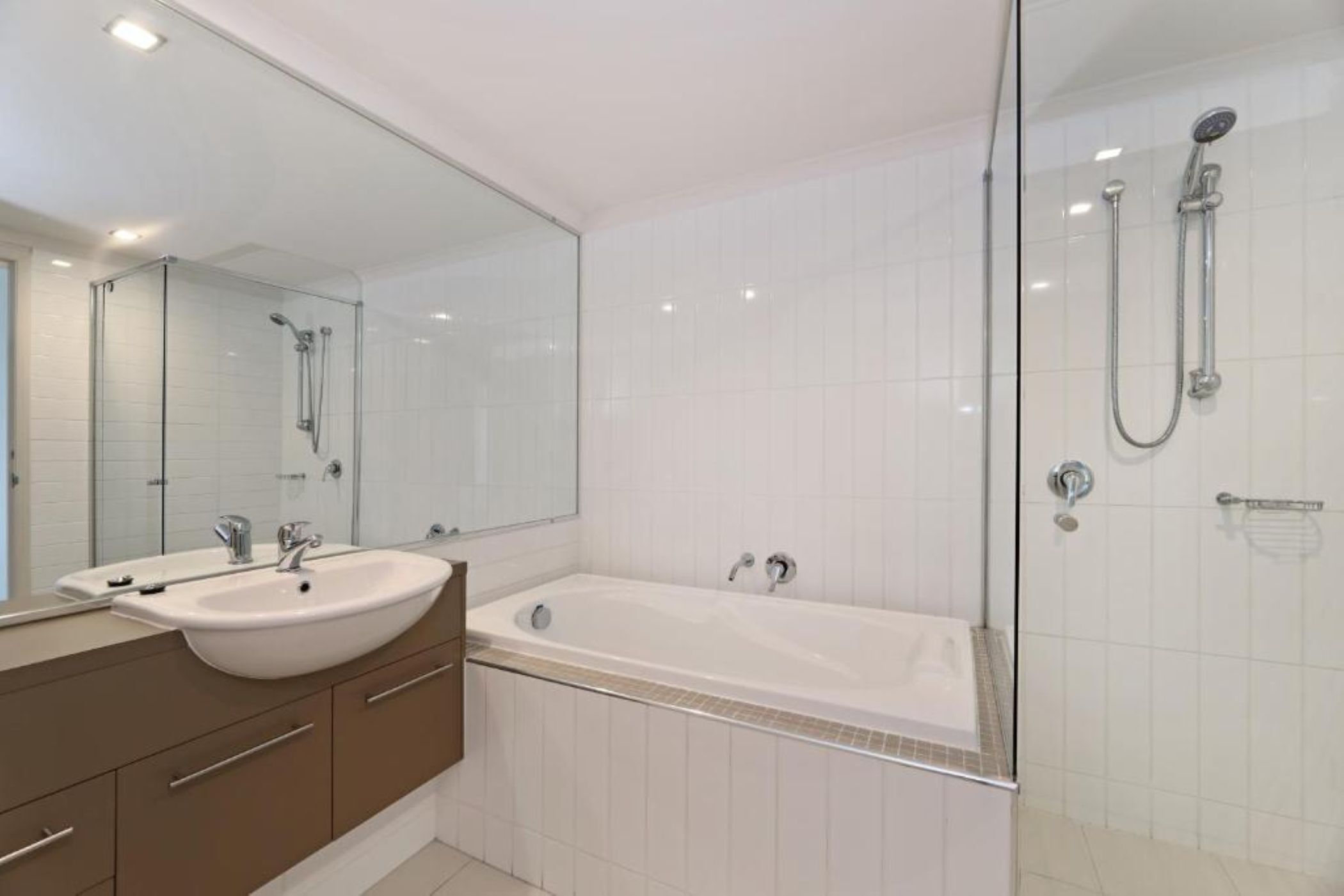 A modern bathroom with a glass-enclosed shower, a large bathtub, and a vanity with a mirror.