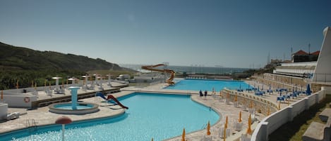 Una piscina al aire libre de temporada, sombrillas, tumbonas