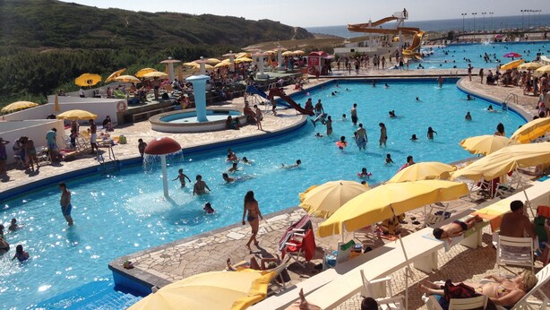 A large outdoor swimming pool with multiple lanes, surrounded by sun loungers and umbrellas. - Sintra Sol - Apartamentos Turisticos (Sintra)
