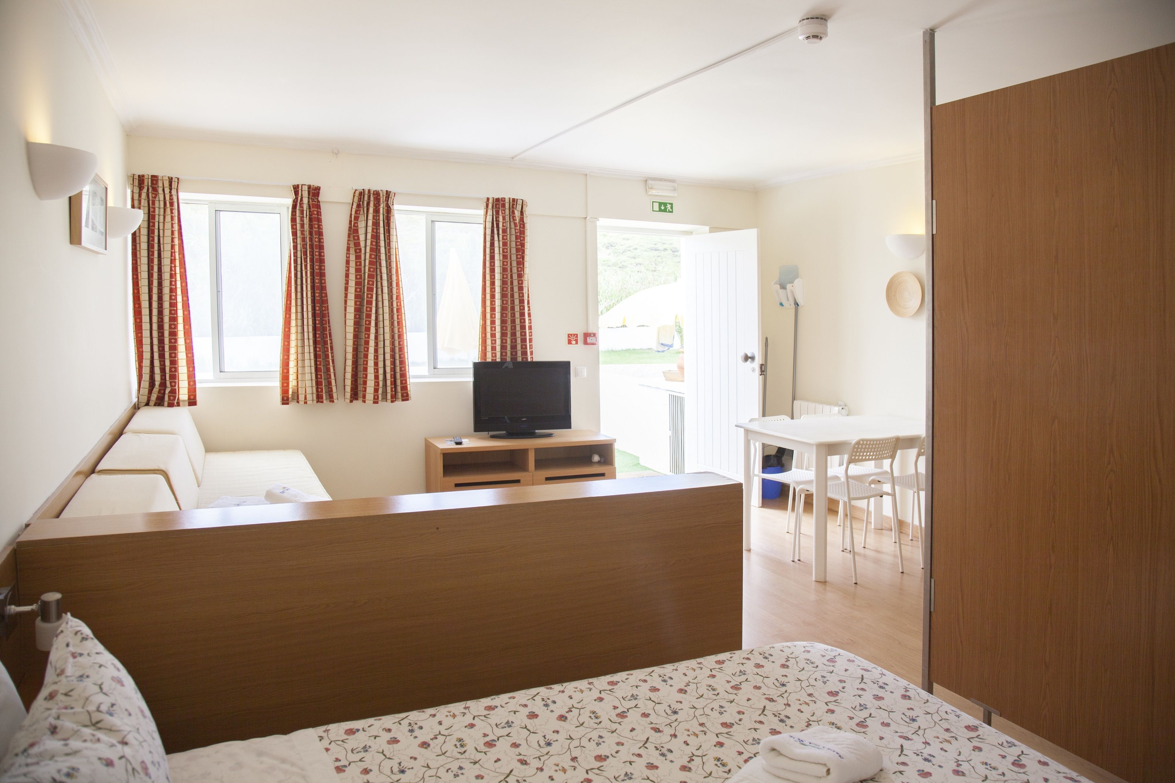 A hotel room with a bed, a TV, a desk, and a chair.