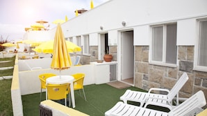 A hotel patio with yellow umbrellas, white lounge chairs, and a small table. - Sintra Sol - Apartamentos Turisticos (Sintra)